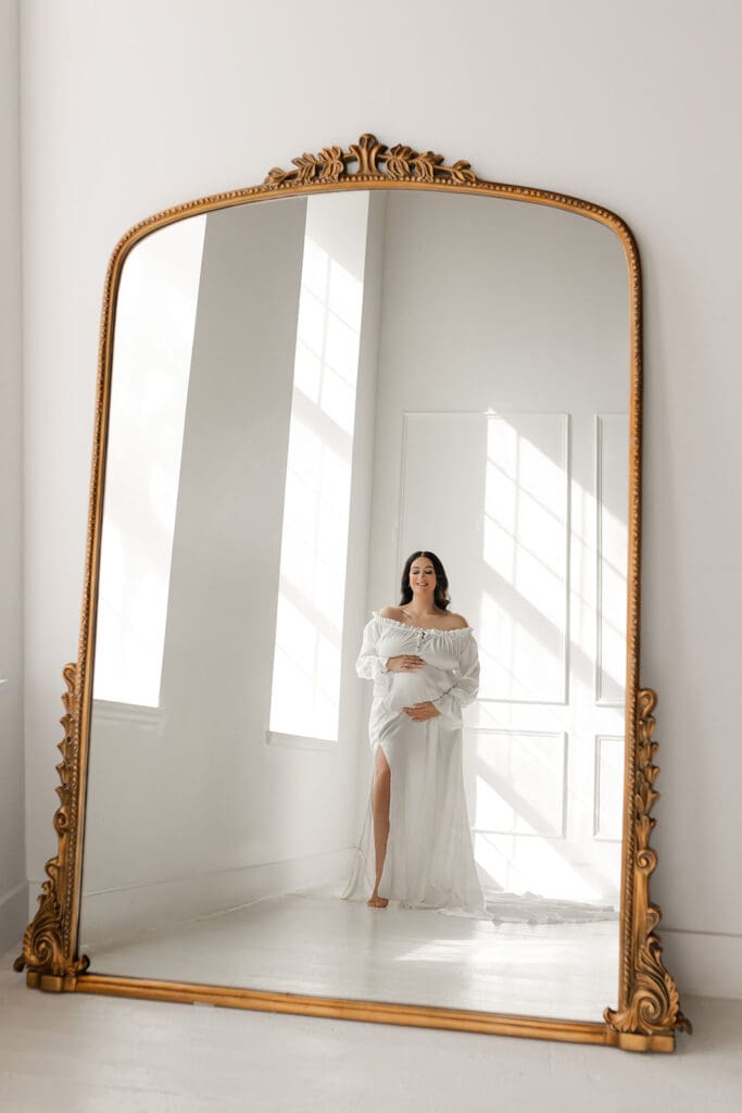 Modern maternity photo in white dress with mirror